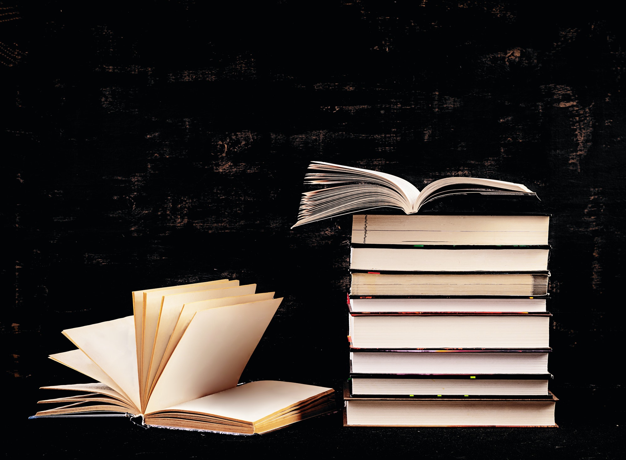 Stack of different books on dark background. Knowledge concept.